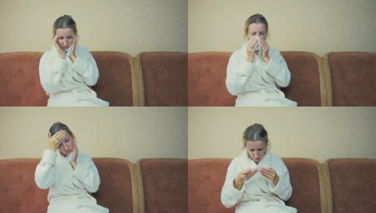 穿着居家长袍的年轻女孩坐在家里的沙发上咳嗽和打喷嚏。4 k。高清在线视频素材下载