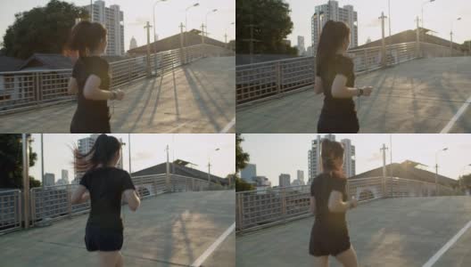 后视图。亚洲女性正在进行户外跑步锻炼。亚洲女运动员穿黑色运动服，而跑在桥上的人行道在城市。健康跑步和户外运动的概念高清在线视频素材下载