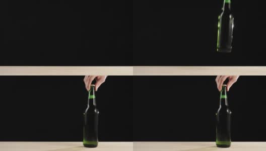 新鲜的啤酒。Hand把一个绿色的瓶子和美味的精酿啤酒放在一张黑色背景的木桌上。冰镇新鲜啤酒与水滴。准备饮料。广角镜头。4 k高清在线视频素材下载