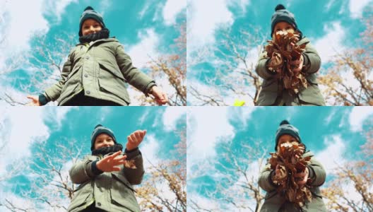 《可爱的小男孩》在秋季向镜头扔落叶——慢镜头高清在线视频素材下载