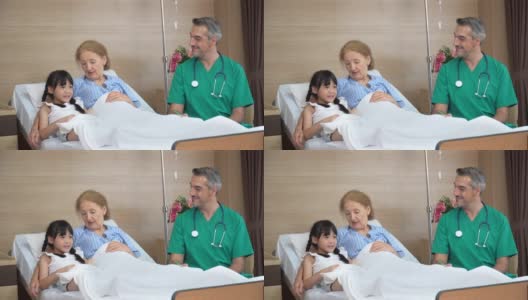 在病房里，医生正和躺在床上陪孙女的老年女病人交谈。物理治疗师探访及与残疾老年女性进行物理治疗。高清在线视频素材下载