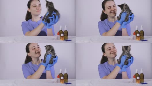 一位身穿蓝色制服的女兽医抱着一只灰色的小猫，微笑着对一只生病的猫说话。高清在线视频素材下载