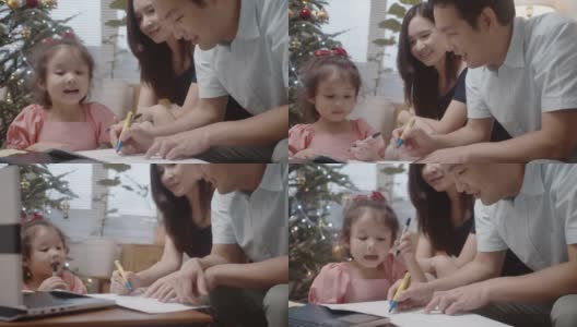 年轻的亚洲父母和可爱的女儿一起在家里制作贺卡高清在线视频素材下载