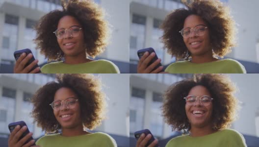 非裔美国妇女在镜头前微笑，手里拿着智能手机，科技高清在线视频素材下载