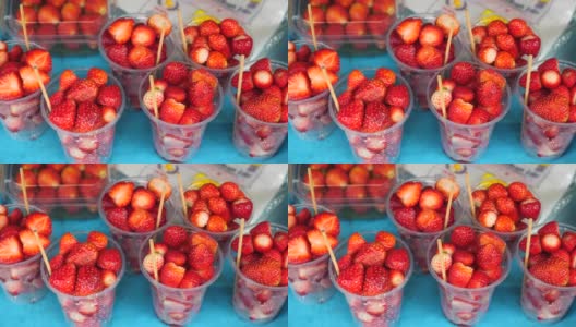 水果市场上盛着新鲜红草莓的塑料杯。当地的农民市场高清在线视频素材下载