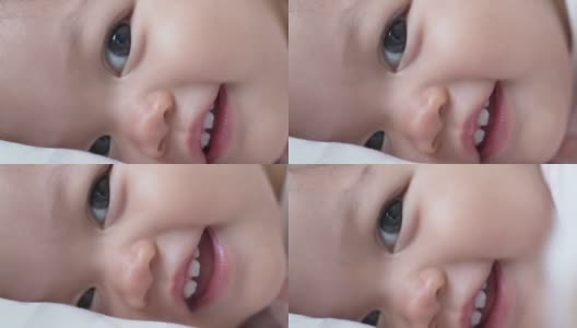 婴儿的特写:喝完奶瓶里的牛奶后，婴儿眨着眼睛微笑。孩子眨眼。娃娃脸开心的笑。亚洲的孩子。高清在线视频素材下载