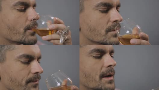 大胡子男子品尝着上等威士忌，吸入着香气，特写镜头。品尝高清在线视频素材下载