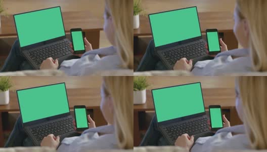 肩上的一个女人使用笔记本电脑和拿着智能手机，都有模拟绿色屏幕。高清在线视频素材下载