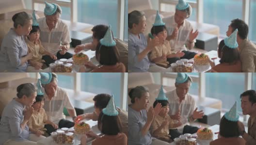 亚洲华人多代同堂在客厅拍手，唱生日歌庆祝6岁男孩的生日高清在线视频素材下载