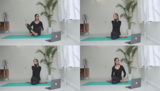 一个亚洲女人在笔记本电脑前做瑜珈练习。高清在线视频素材下载