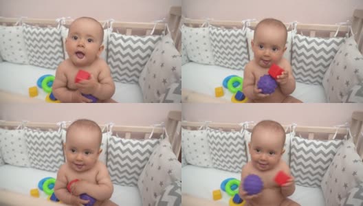 一幅新生儿坐在婴儿床里的画像。这孩子玩玩具是为了发展手的运动技能高清在线视频素材下载