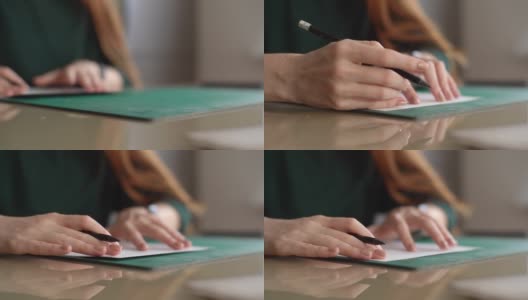 不知名女设计师的特写手把白纸放在绿色的橡胶裁纸垫上，在桌子上做记号。高清在线视频素材下载