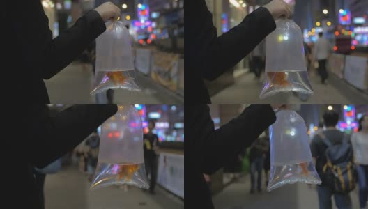 慢镜头拍摄于中国香港，一个繁忙的街头女孩拿着一个装着水和金鱼的透明袋子高清在线视频素材下载