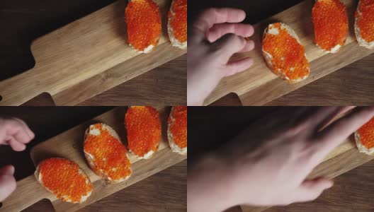 一个男人的手把带有红鱼子酱的三明治放在一块板上。高清在线视频素材下载