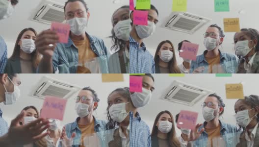 小组头脑风暴的亚洲人把便利贴贴在窗户上。团队合作的商务人士戴上口罩，可以防止新冠病毒感染，在办公室讨论和分享解决问题的想法。高清在线视频素材下载