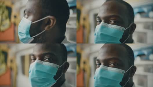 一个黑人非洲裔美国EMS专业医护人员的近距离肖像看着相机，而戴着一个安全面罩在救护车。医院外的紧急医疗技术员高清在线视频素材下载