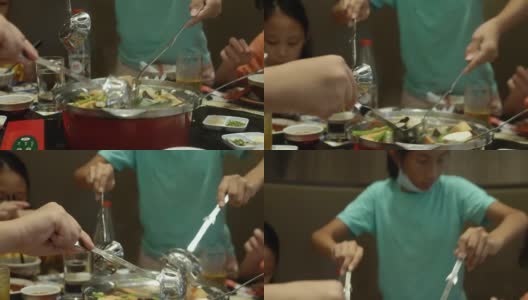 快乐的亚洲儿童与家人一起在餐厅吃素喜烧、涮涮锅或火锅，生活方式理念。高清在线视频素材下载