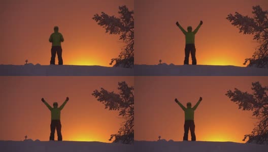一个徒步旅行者站在白雪皑皑的山顶上，在日落的天空中自豪地伸出双臂高清在线视频素材下载