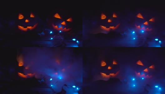 万圣节的时候，两个南瓜里面有一张可怕的脸在发光，晚上在黑暗中烟雾从左边传到右边。高清在线视频素材下载