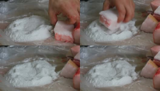 一名男性屠夫用盐将大块猪肉裹在肥肉和猪肉皮中高清在线视频素材下载
