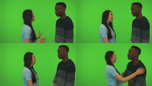 一个年轻的亚洲女人和一个年轻的黑人男人拥抱和交谈-绿色的银幕工作室高清在线视频素材下载