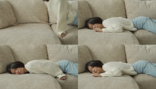 疲惫的年轻亚洲女人倒在沙发上。一个又累又懒的女人独自睡在家里的沙发上高清在线视频素材下载