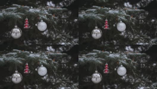 圣诞球和人字骨在冷杉树枝上摇摆，外面下雪了高清在线视频素材下载