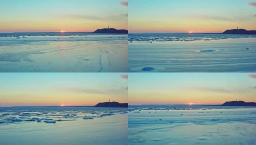 从空中俯瞰冰冻的冬季海面上的日落。一架无人机在日出时降落在海面上。在融化的浮冰和工业城市上空飞行。全球变暖。生动的色彩斑斓的天空。工业厂房高清在线视频素材下载