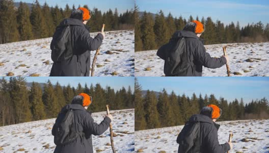 侧面的年轻徒步旅行者与背包和手在雪山上攀登在田野。运动的家伙在阳光明媚的雪地上徒步旅行。健康积极的生活方式。冬季森林的背景。慢镜头高清在线视频素材下载