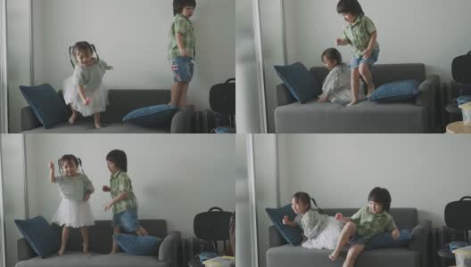 泰国可爱的小女孩和蹒跚学步的男孩在客厅的沙发上跳舞和玩耍-库存视频高清在线视频素材下载