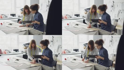 富有魅力的服装设计师企业家们正在用粉笔勾勒出人物轮廓，用平板电脑工作，还会说话。忙碌的一天在成功的裁缝店概念。高清在线视频素材下载