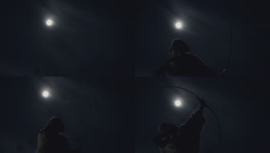 在满月之夜狩猎的原始人。从下面的侧面看原始男性与弓和箭狩猎在夜晚的自然在黑暗的天空与满月的背景高清在线视频素材下载