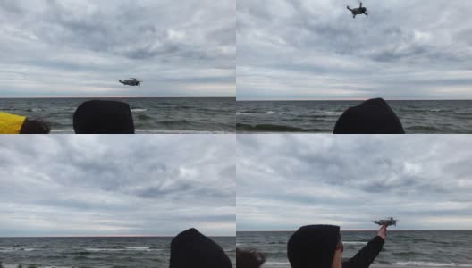 男人和女人站在海边，以慢动作驾驶无人机飞向天空高清在线视频素材下载