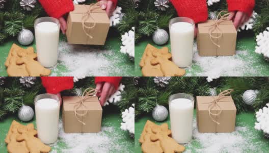 穿着红色毛衣的手把一个工艺礼品盒放在桌子上，上面有圣诞饼干、一杯牛奶和圣诞装饰品。圣诞老人送给孩子们的礼盒。给圣诞老人的圣诞礼物。高清在线视频素材下载