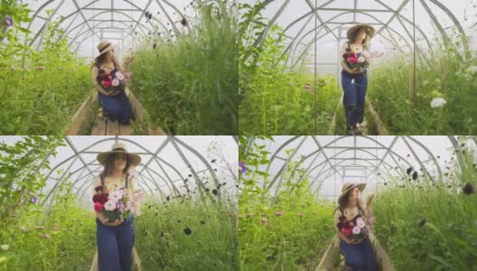 快乐的女人捧着花束沿着盛开的植物走着高清在线视频素材下载