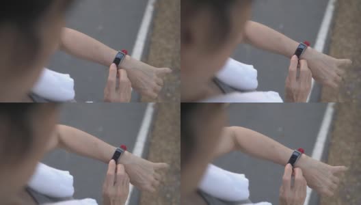 一名亚洲老年妇女在公园的树下触摸智能手表活动跟踪器。手指敲击运动手表卡路里和心率信息。慢动作轨道拍摄。医疗保健俯视图。高清在线视频素材下载