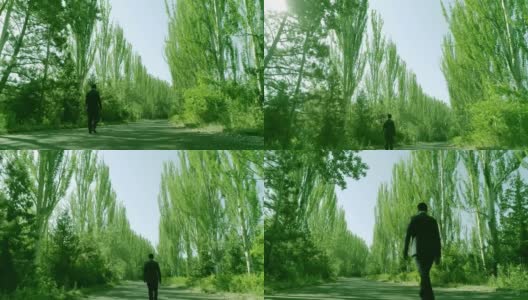 后视镜:西装革履的人独自穿过森林或花园的树木。孤独的男孩走在林间的小径或人行道上，林间有高大的绿树。缓慢的运动。无人机高清在线视频素材下载