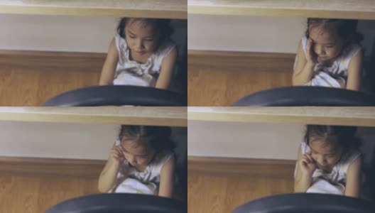 俯视图的亚洲小女孩在桌子下哭泣，悲伤，压抑，痛苦，不安和害怕的表情，这是由于家庭惩罚和暴力，这是社会问题。高清在线视频素材下载