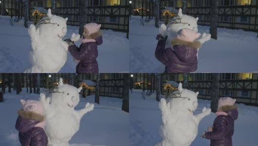 小女孩在雪地里堆雪人，看着它高清在线视频素材下载