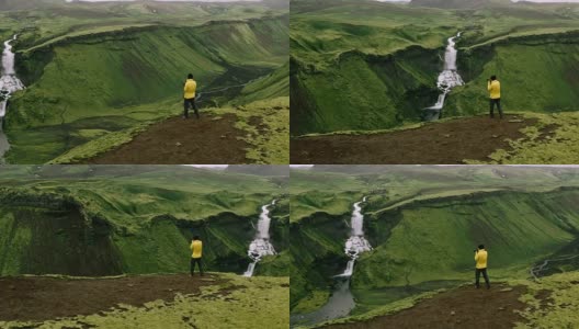 航拍探险旅行摄影师站在悬崖边拍摄瀑布山景高清在线视频素材下载