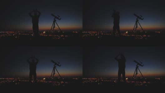一个人的剪影，望远镜和城市街灯下的星空。高清在线视频素材下载