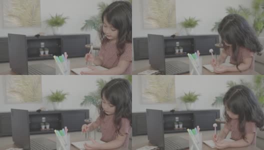 混合的亚洲学龄前女孩在家里使用笔记本电脑电子学习，放大在线虚拟课堂，家庭教育，新常态概念高清在线视频素材下载