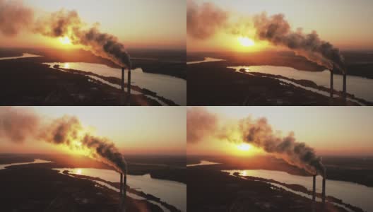 夜晚河流附近的空气污染严重。太阳下山时，大量有害的烟雾排到空气中。生产过程中冒出黑烟的烟囱。鸟瞰图。高清在线视频素材下载