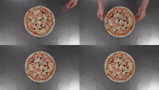 从空中拍摄的一组镜头中，男性的双手将一盘美味的披萨放到了一张金属桌子上。传统意大利美食概念高清在线视频素材下载