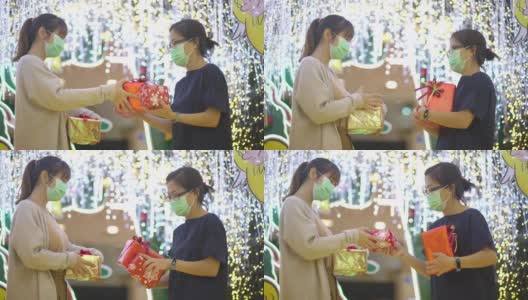 亚洲妇女戴着防护面具在商场的圣诞活动中交换礼物高清在线视频素材下载