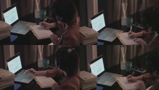 亚洲华人美丽的女人使用笔记本电脑工作，在家自习室书写耳机高清在线视频素材下载