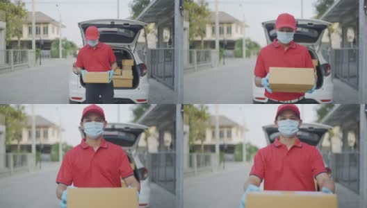 4 k慢动作视频。一名身穿红色制服的男性快递员一边送包裹一边看着摄像头。新标准的概念。高清在线视频素材下载