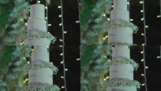 婚礼蛋糕装饰以鲜花和浪漫的灯光背后高清在线视频素材下载