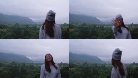 模糊的慢镜头，一个女旅行者在雾天看美丽的山景时挥手高清在线视频素材下载
