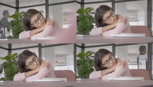 一位漂亮迷人的办公室女职员戴着眼镜，疲惫地在桌子上打盹高清在线视频素材下载